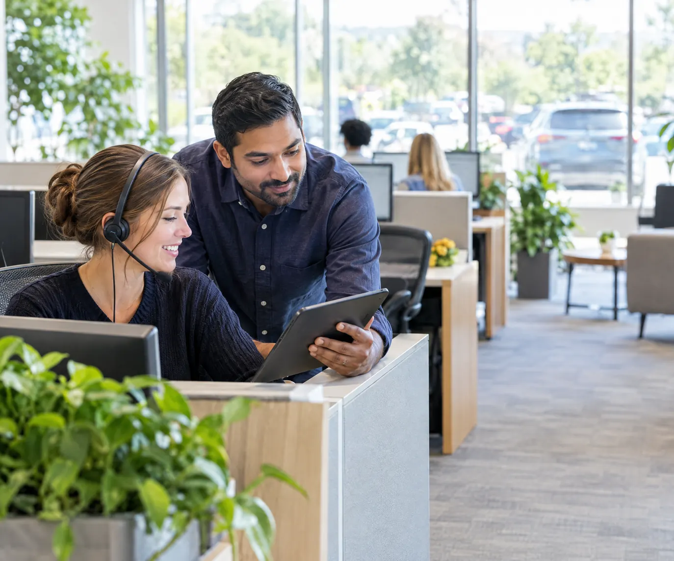 A fleet coordinator with a headset and a colleague with a tablet on a bright operations floor